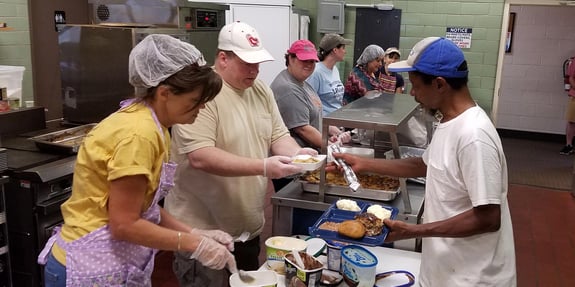 Group of people serving food at a soup kitchen